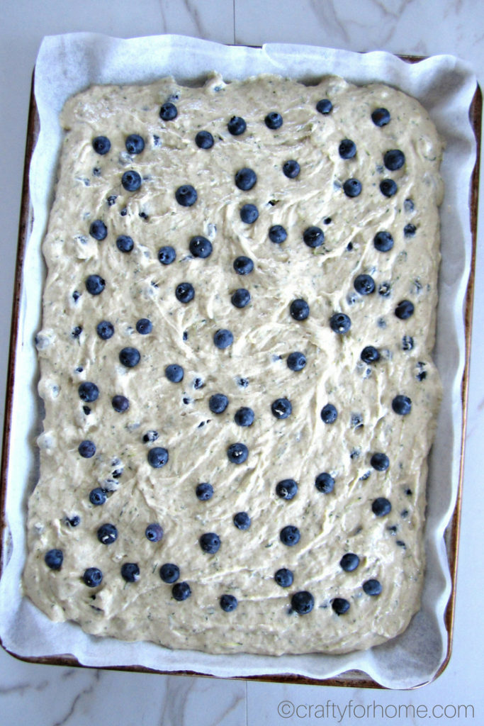 Easy dairy-free blueberry zucchini cake recipe with the lemon icing glaze. Bake it on the sheet pan to make cake bars. #dairyfree #sheetcake #zucchinicake #lemonicing for full recipe on craftyforhome.com