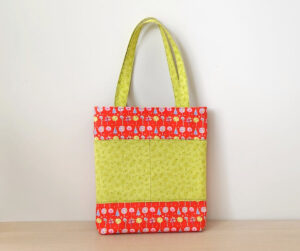 Library tote bag with green fabric pocket.
